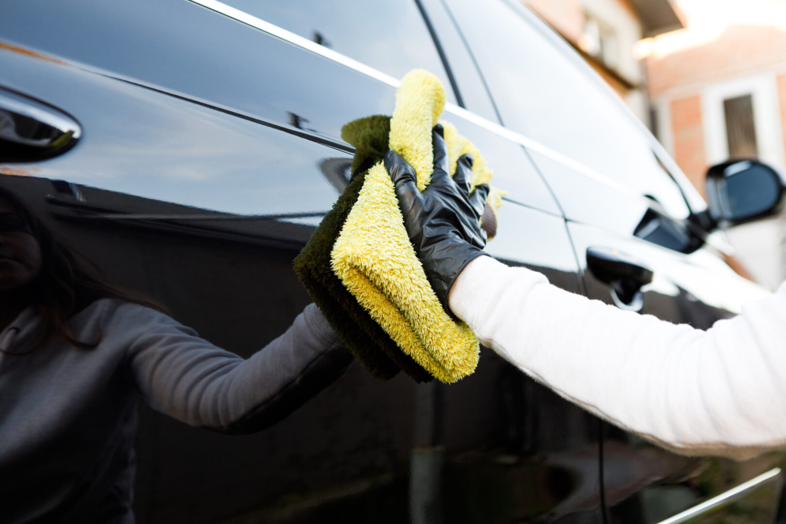 woman polishes the car uses microfiber cloth and polish to wipe the cars body with polish